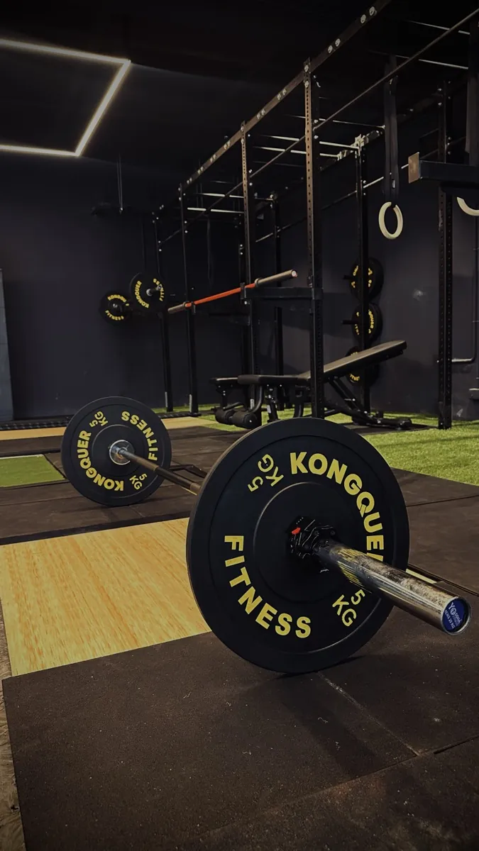Branded Kongquer bumper plates loaded on a barbell across the training floor